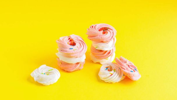 Dulces blancos y rosados sobre fondo amarillo - Foto, Imagen