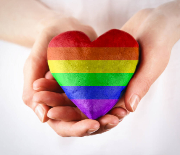 Rainbow LGBT sydän naisten käsissä varastossa kuvia. Naiskädet antavat sateenkaaren sydänkuvan. Sateenkaari ylpeys lippu sydämen muotoinen kuvia. LGBT sateenkaaren sydämen rakkauden symboli - Valokuva, kuva