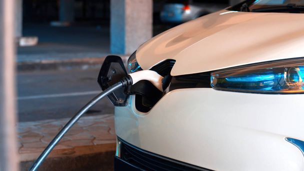 Подключение зарядного устройства к белому электрическому автомобилю - Фото, изображение