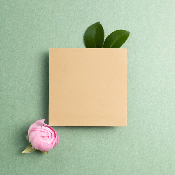 Kraft bloc de notas con flor sobre fondo verde. vista superior, espacio de copia - Foto, Imagen
