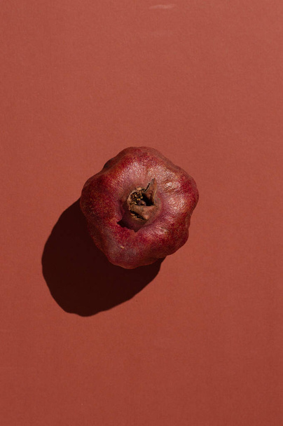 On a brown background, ripe pomegranate in harsh lighting. View from above. - Fotoğraf, Görsel