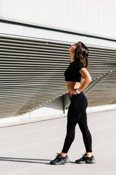 Fit Mädchen im schwarzen Fitness-Outfit posiert für ein Foto. Vereinzelt vor dem ausgeblasenen weißen Hintergrund. Gesunder Lebensstil. - Foto, Bild