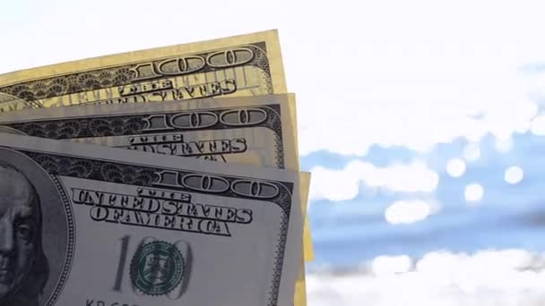 Dollar rekeningen op de achtergrond van de zee op zonnige dag close-up. - Video