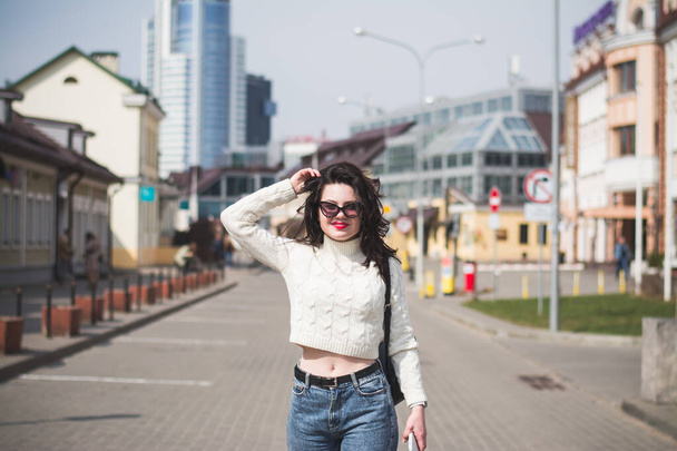 Beautiful young girl student hipster walks along the street of her city in the spring - Photo, Image