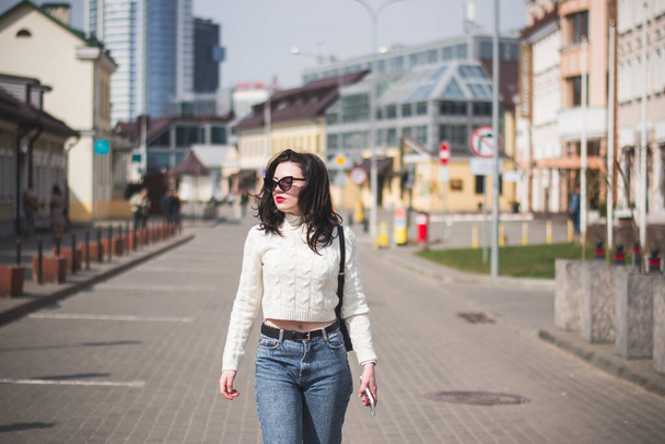 Beautiful young girl student hipster walks along the street of her city in the spring - Фото, зображення