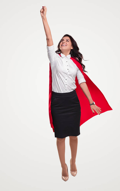 Happy businesswoman in superhero cape flying - Foto, imagen