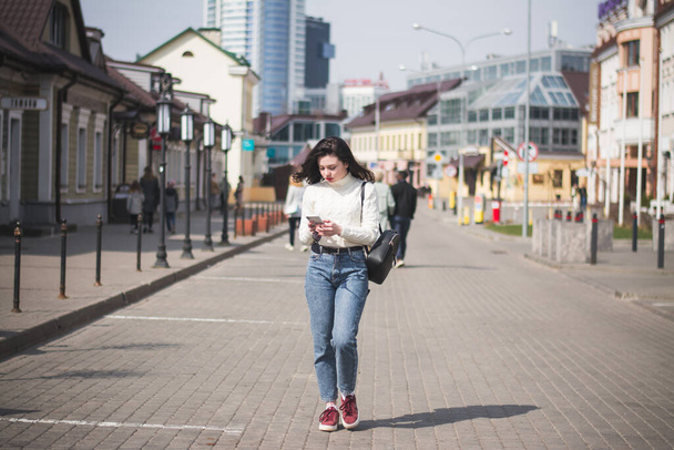 Beautiful young girl student hipster walks along the street of her city in the spring - 写真・画像