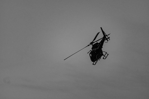 Вертолет, обеспечивающий поддержку с воздуха во время операции гражданской полиции по борьбе с организованной преступностью и незаконным оборотом наркотиков, в общине (Фавела) в Рио-де-Жанейро, Бразилия. - Фото, изображение