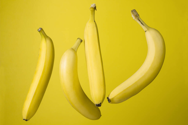 Bananas on a yellow background. Bright fruits. Four bananas on a colored background - Fotoğraf, Görsel