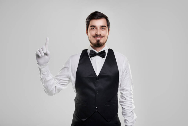 Positive waiter smiling and pointing up - Foto, immagini