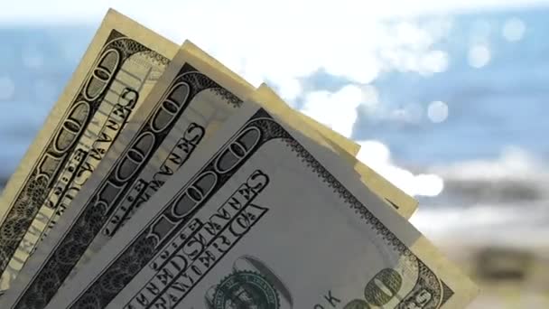 Dollar rekeningen op de achtergrond van de zee op zonnige dag close-up. - Video