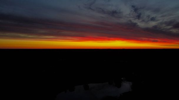 Hermosa vista naranja y roja al atardecer desde la vista del dron con reflejo del lago en el suelo. Paisaje aéreo. - Foto, imagen