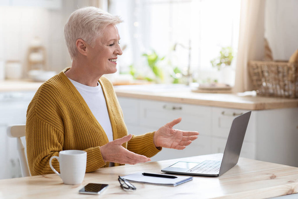 Vrolijke oudere vrouw met online klasse, praten met tutor - Foto, afbeelding
