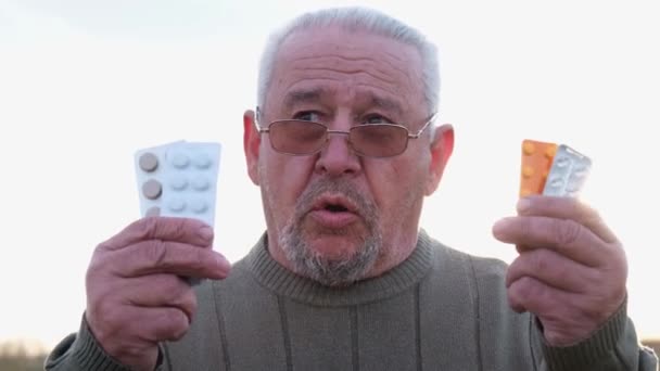 Abuelo gris enfermo con pastillas en las manos. - Imágenes, Vídeo