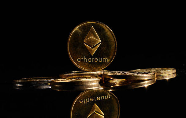 新しい暗号通貨Ethereum ETH 2.0は、黒い背景を持つビットコインの上にあります。Etherロゴで黄金のコインを閉じます。分散型デジタル通貨のヒープ。暗号化の支払い。電子マネー - 写真・画像