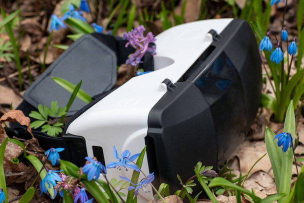 3D Virtuális valóság headset szemüveg tavaszi kék vad virágok. VR technikai felszerelés szemüveg közelről. Optikai szórakoztató rendszer okostelefonokhoz - Fotó, kép