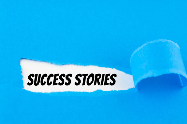 Текстовые истории успеха появляются за разорванной голубой бумагой - Фото, изображение