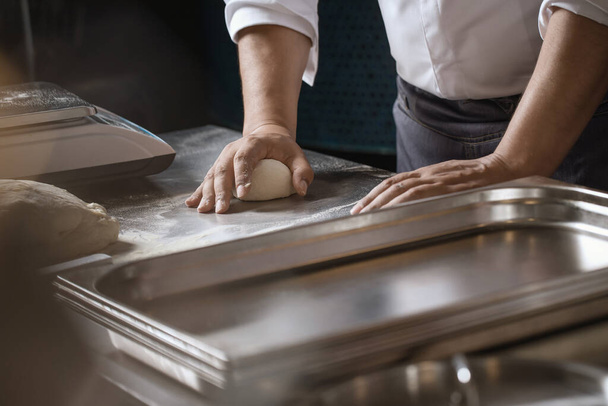 Making dough for bread by male hands in restaurant kitchen. Cooking concept. - Photo, image