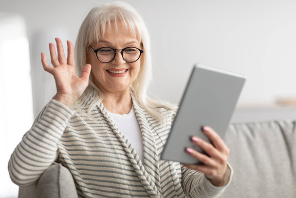 Mulher feliz usando tablet para chamada de vídeo e acenando - Foto, Imagem