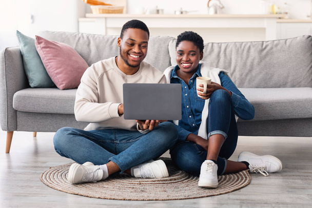 African american couple sitting on floor, using laptop - Foto, Imagen
