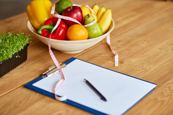 Widok z góry dietetyk, dietetyczne miejsce pracy z blankiem na plan diety, długopis, taśma pomiarowa i miska ze zdrowymi warzywami i owocami, opieka zdrowotna i dieta, prawidłowe odżywianie i odchudzanie koncepcji wellness. - Zdjęcie, obraz