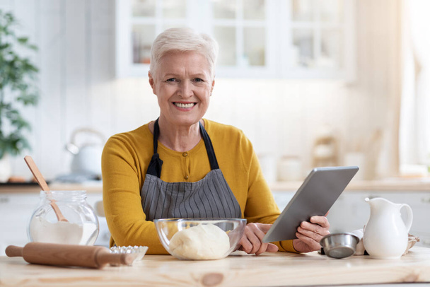 Feliz anciana cocinando por recetas de Internet - Foto, imagen