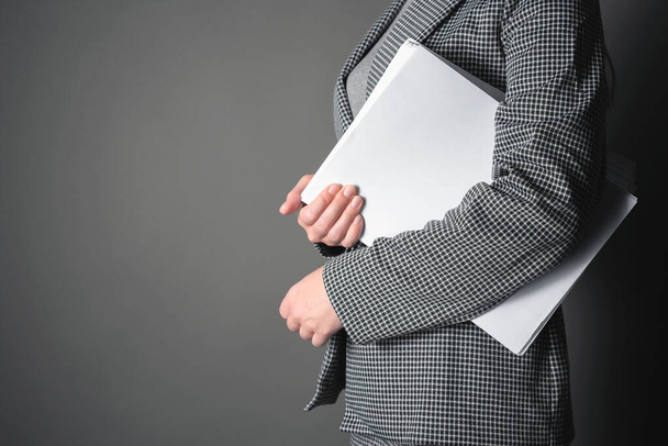 Secretary with a heap of documents in hand on a gray background. - Zdjęcie, obraz