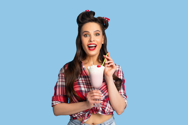 Портрет гламурной женщины пинап в ретро стиле носить чувство счастья во время питья молочный коктейль на синем фоне - Фото, изображение