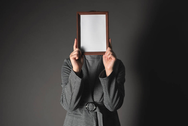 Diploma or certificate mockup. Woman is hiding her face behind an empty photo frame border on a gray background. - Zdjęcie, obraz