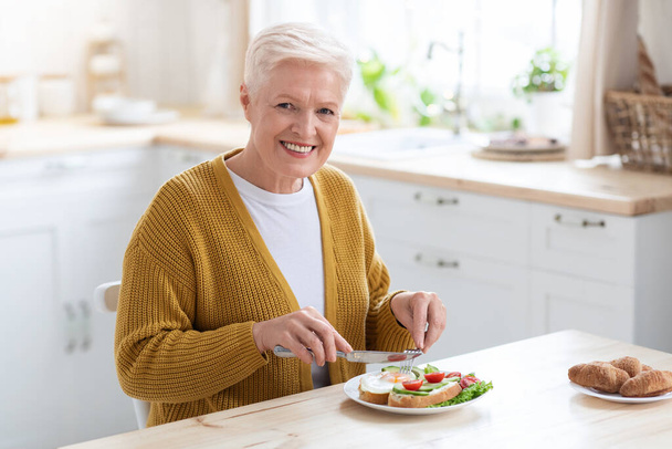 Cheerful healthy senior woman enjoying her lunch at home - 写真・画像