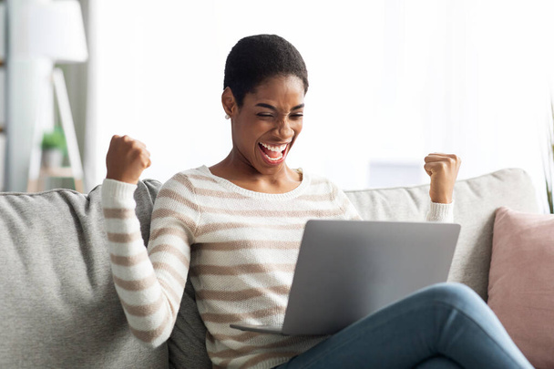 Excitado excitado mulher negra celebrando o sucesso com laptop em casa - Foto, Imagem