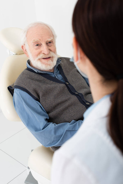 starší pacient v zubním křesle při konzultaci s lékařem na klinice - Fotografie, Obrázek