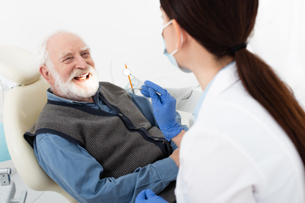 smiling senior man having teeth treatment by dentist in latex gloves in dental clinic - Foto, imagen