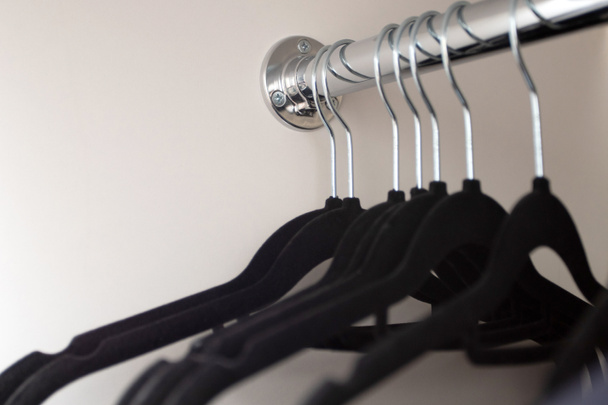Black hangers in the closet. Hangers in the cabinet on the rod. Empty wardrobe. - Фото, зображення