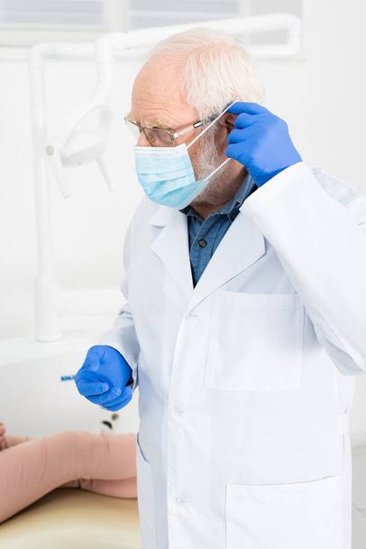 tandarts in latex handschoenen met medisch masker in tandheelkundige kliniek - Foto, afbeelding