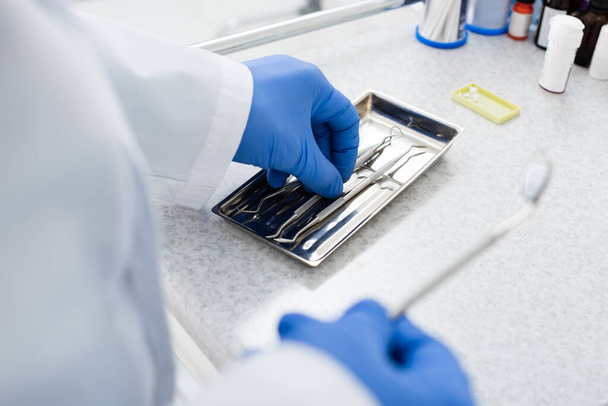 cropped view of dentist in latex gloves taking medical equipment from tray on medical table - 写真・画像