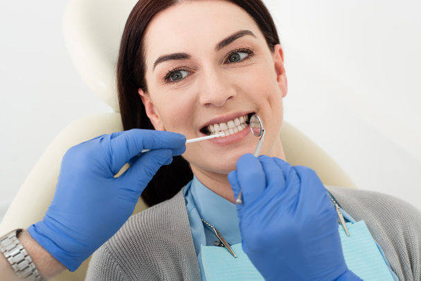 Стоматолог вивчає зуби дорослої жінки зі зондом і дзеркалом в лікарні
 - Фото, зображення
