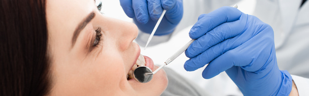 vista de cerca de la mujer adulta que tiene examen de dientes por el médico en guantes de látex en la clínica, bandera - Foto, Imagen