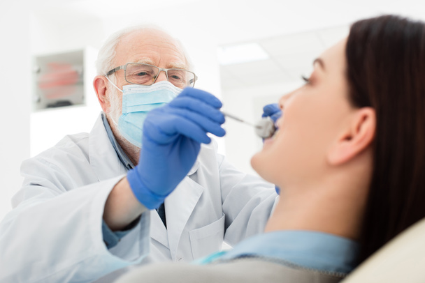 dentista sênior fazendo exame dos dentes da mulher na cadeira dental - Foto, Imagem