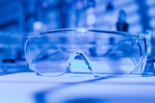 Lunettes de protection de chercheur scientifique sur une table de laboratoire, avec un environnement de lumière bleue - Photo, image