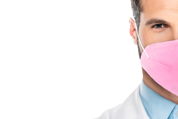 bijgesneden weergave van de mens in roze ffp2 medisch masker kijken naar camera geïsoleerd op wit  - Foto, afbeelding