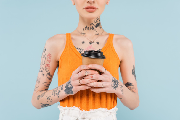обрезанный вид татуированной женщины с бумажной чашкой, изолированной на синий - Фото, изображение