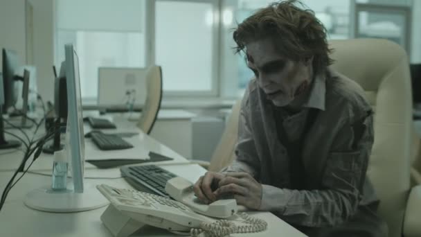 Captura de mão de empresário zumbi com maquiagem SFX assustador sentado na mesa e gritando para o telefone ao tentar fazer chamada - Filmagem, Vídeo