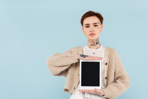 young woman with tattoos holding digital tablet with blank screen isolated on blue - 写真・画像