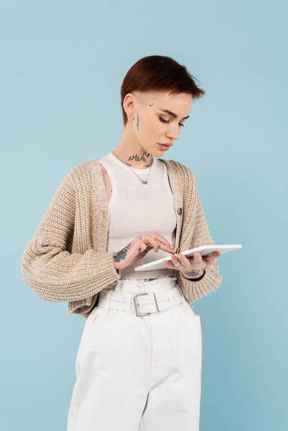 young woman with tattoos using digital tablet isolated on blue - Fotografie, Obrázek