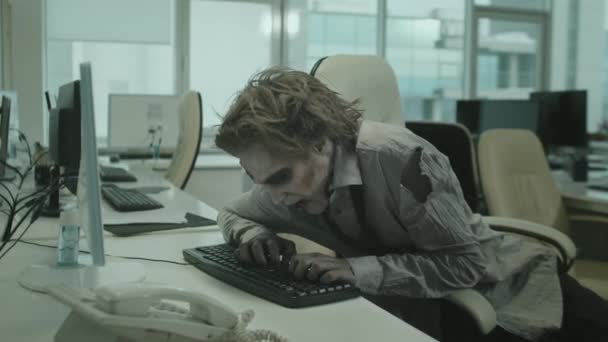 タイプしようとしている間、彼の手で机やスマッシングキーボードに座ってゾンビオフィスの労働者の中ショット - 映像、動画