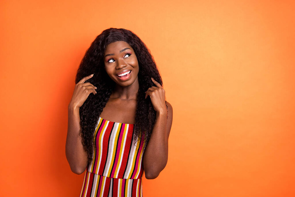 Photo of dreamy dark skin cheerful young lady look empty space summer isolated on orange color background - 写真・画像