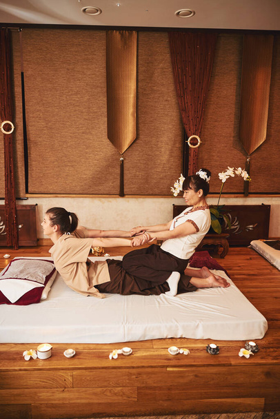 Uzman müşteriyi germek için Tayland masaj metodu kullanıyor - Fotoğraf, Görsel
