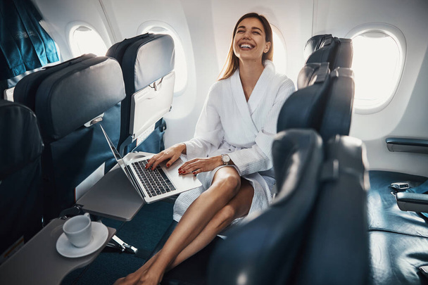 Lady on plane giving a laugh while working on laptop - Foto, Bild