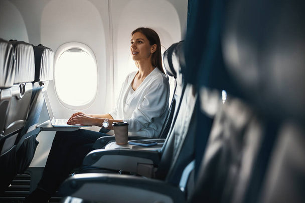 Calm woman sitting by the airplane porthole alone - Foto, imagen